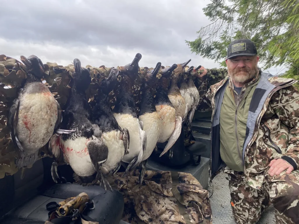 Hunter with diver ducks laid across the front of the boat