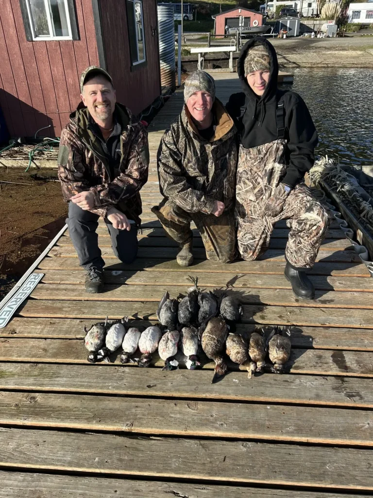 Three hunters on a dock with their diver duck harvest