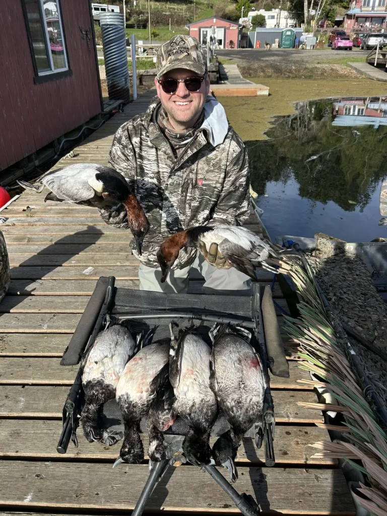 Hunter on a dock with a row of diver ducks